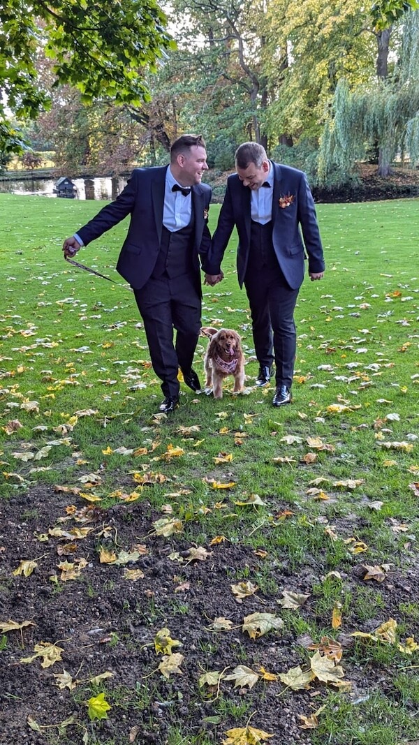Wedding couple holding hands whilst walking their dog