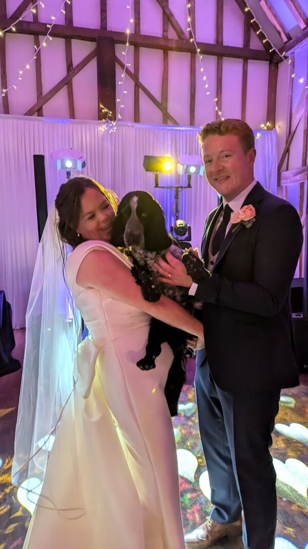 Wedding couple on the dance floor holding their dog