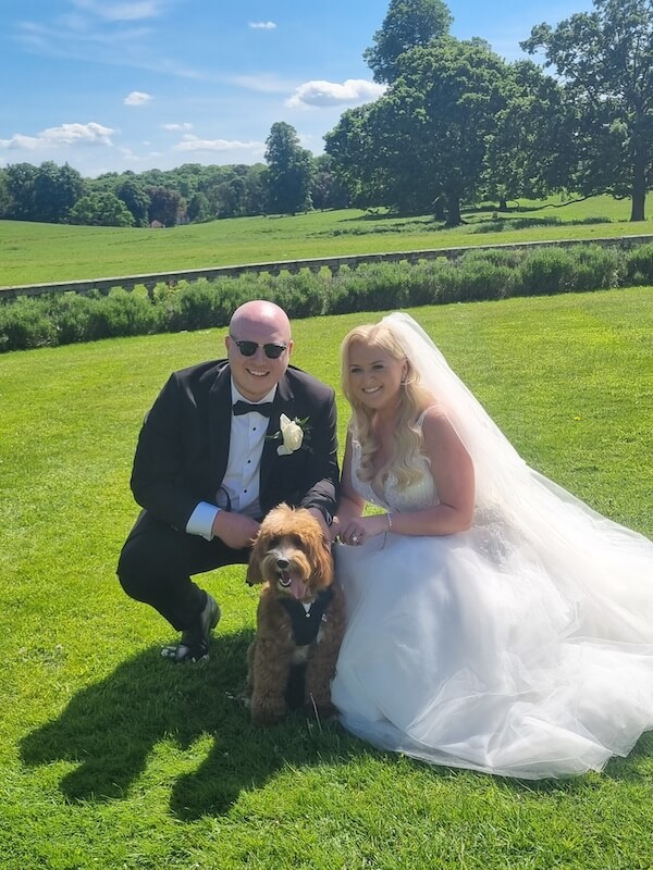 Wedding couple crouched down posing with their dog