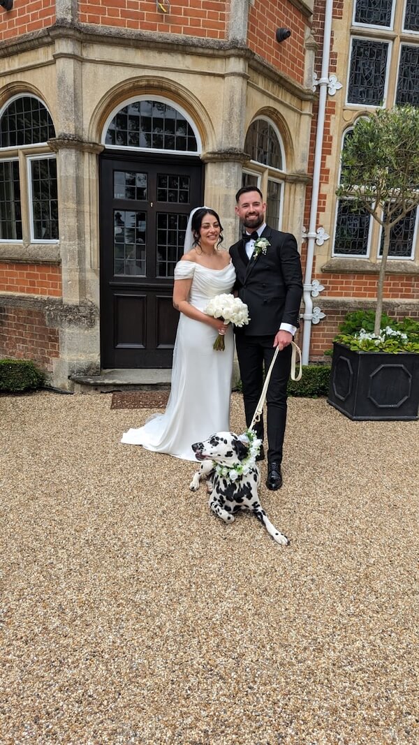 Wedding couple posing in front of a building with their dog